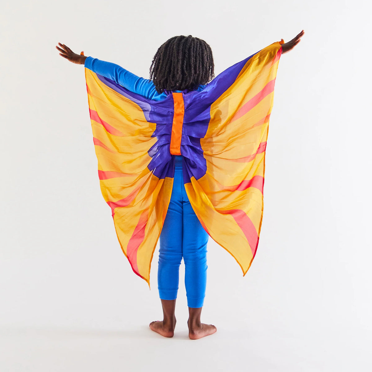 Child wearing an all blue outfit, facing away from the camera to display purple, yellow, and orange pterodactyl wings