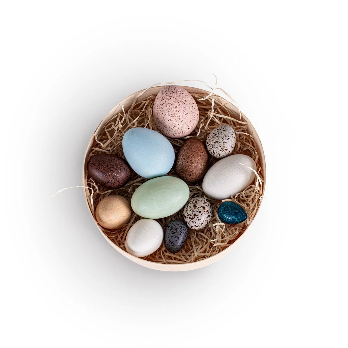 Assorted small wooden eggs in a round wooden box on a white background