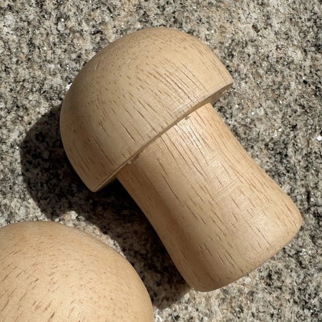 Wooden mushroom-shaped shaker on a textured surface
