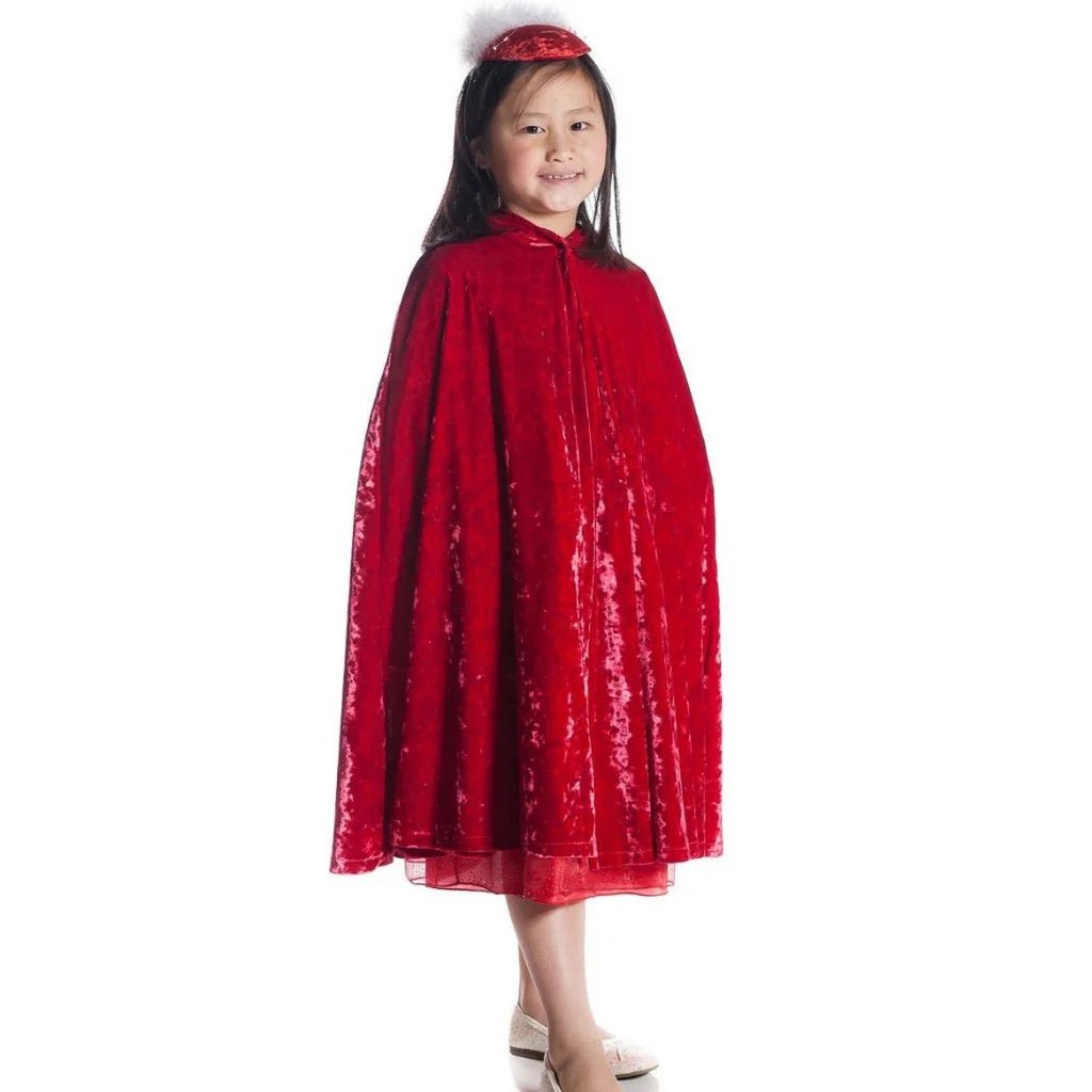 Child wearing a red crushed velvet cape and feathered cap on a white background