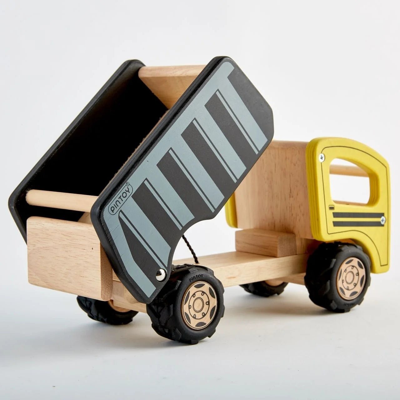 A wooden toy dump truck with a natural wood body, a yellow cab, and a black and gray striped dump bed, shown on a clean white background.
