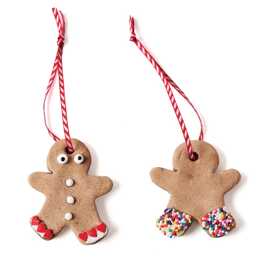 Two gingerbread man ornaments with candy cane strings on a white background