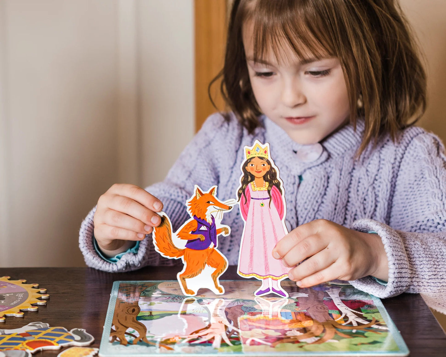 Child playing with a princess and fox paper cutout on a table