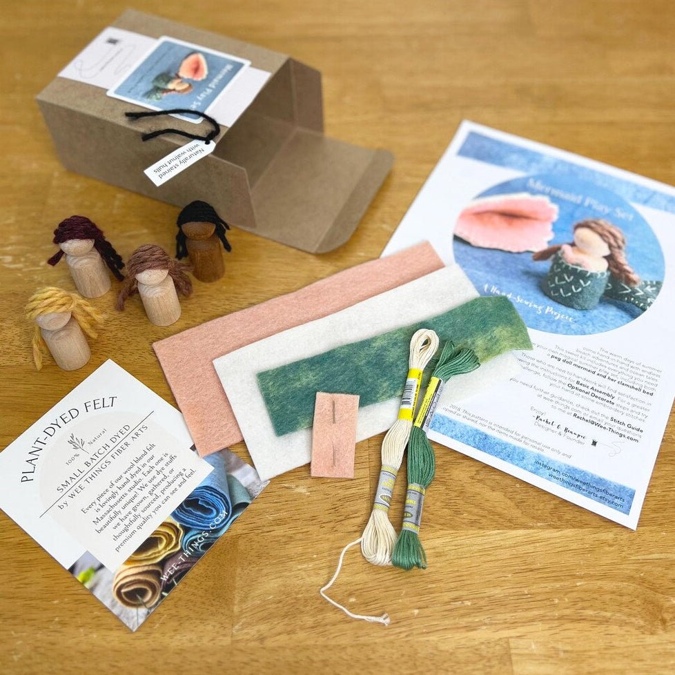 Crafting kit with felt materials, tools, and instructions on a wooden surface