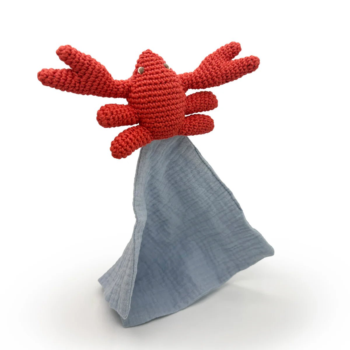 Red crocheted crab toy with an attached gray blanket on a white background