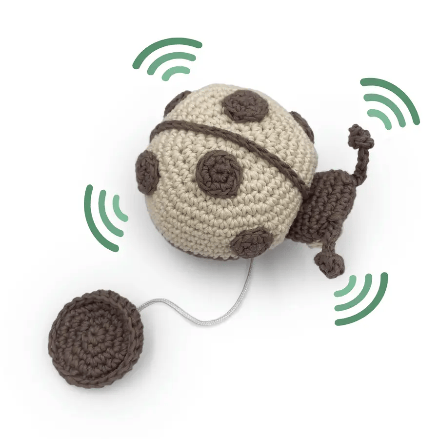 GIF of crocheted beige and gray ladybug toy with a string with wiggly lines to show vibration