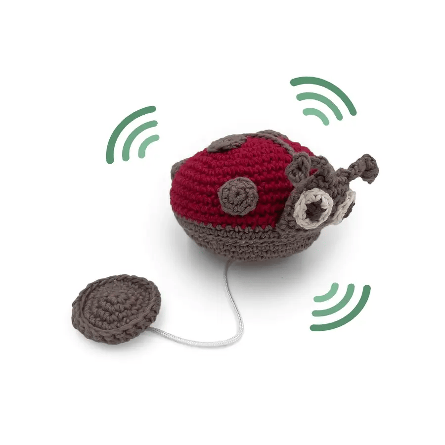 Crocheted red and grey ladybug toy with a string and wobbly lines to show vibration