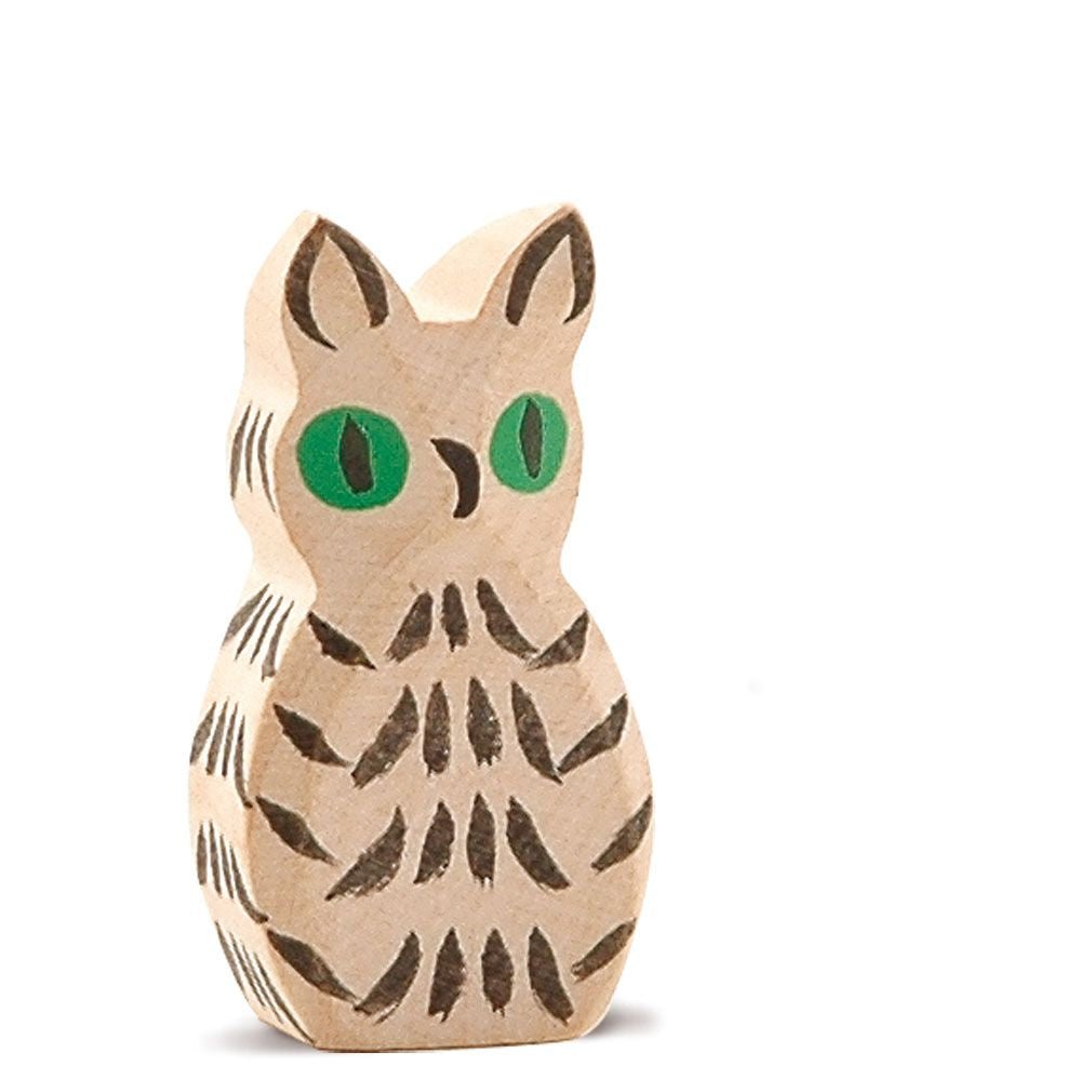 White wooden owl figurine with green eyes on a white background