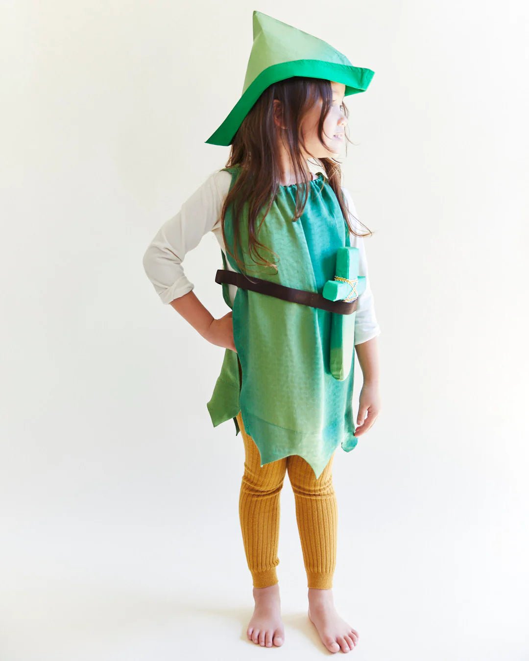 Child wearing a green Peter Pan costume with a pointed hat on a white background
