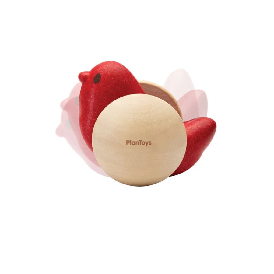 Side view of red wooden bird toy in motion on a white background
