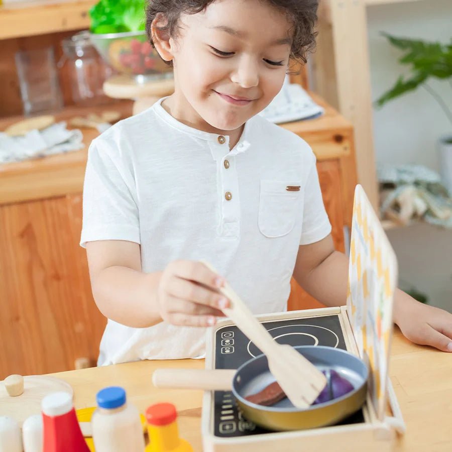 Child playing with a toy kitchen set in a kitchen setting