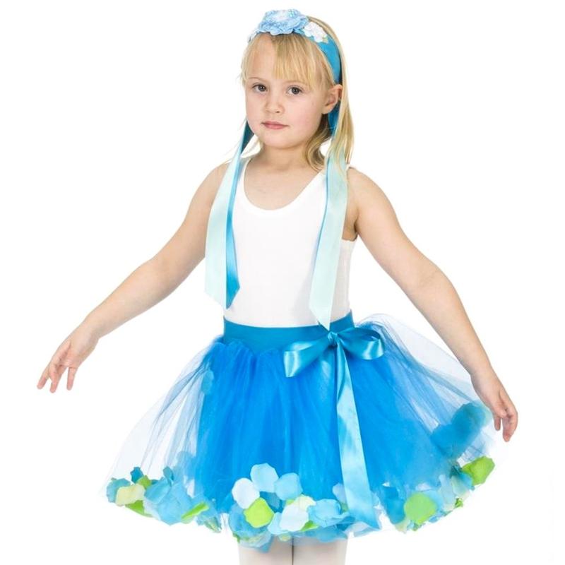 A young girl modeling a blue and white tutu costume with a white tank top, a blue headband, and a blue tutu skirt decorated with blue, white, and green flower accents.