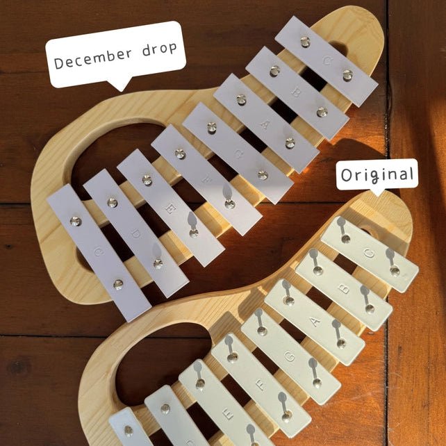 Two xylophones sitting next to each other on a wooden surface, one labeled December Drop, one labeled Original