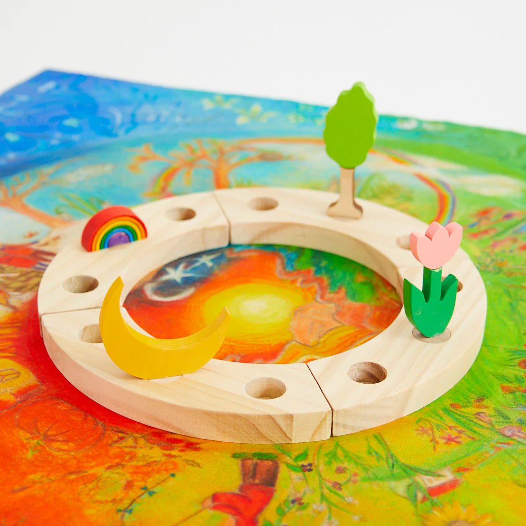 Wooden birthday ring with circular design featuring a moon, sun, rainbow, tree, and flower on a colorful background.