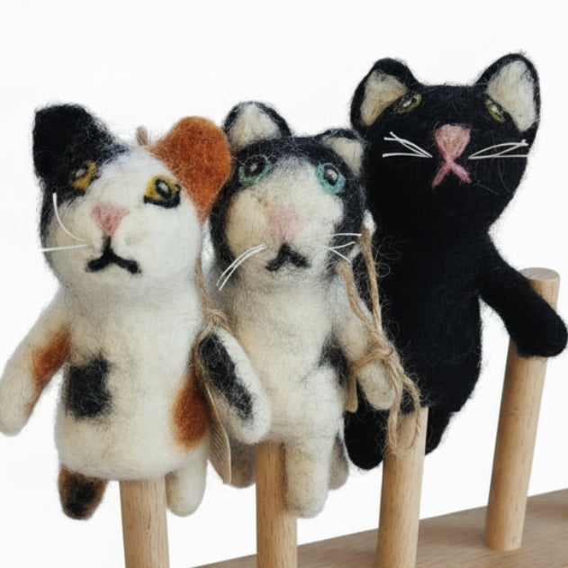 Three cat finger puppets on a stand on a white background