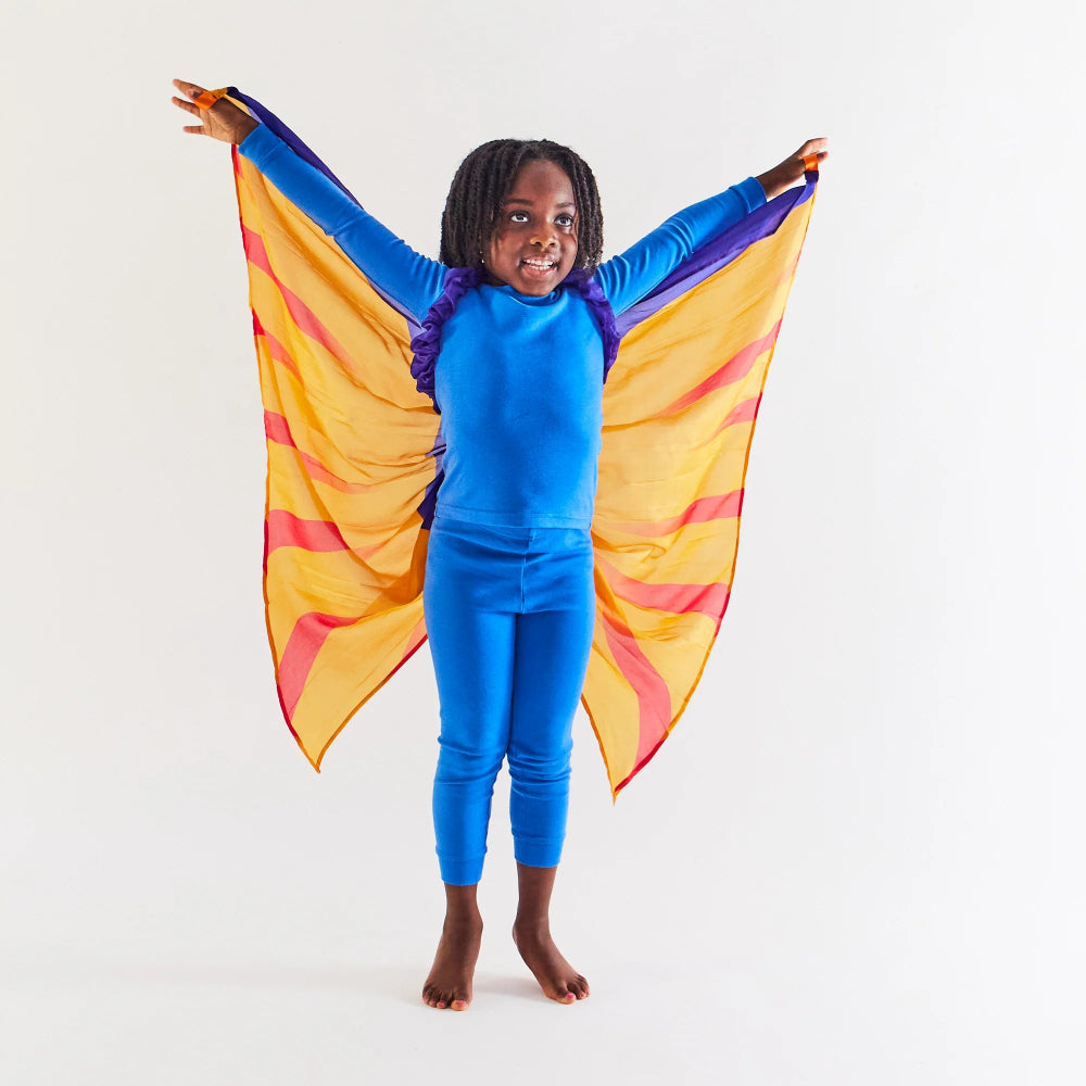 Child wearing an all blue outfit, and yellow and orange silk wings with purple accents