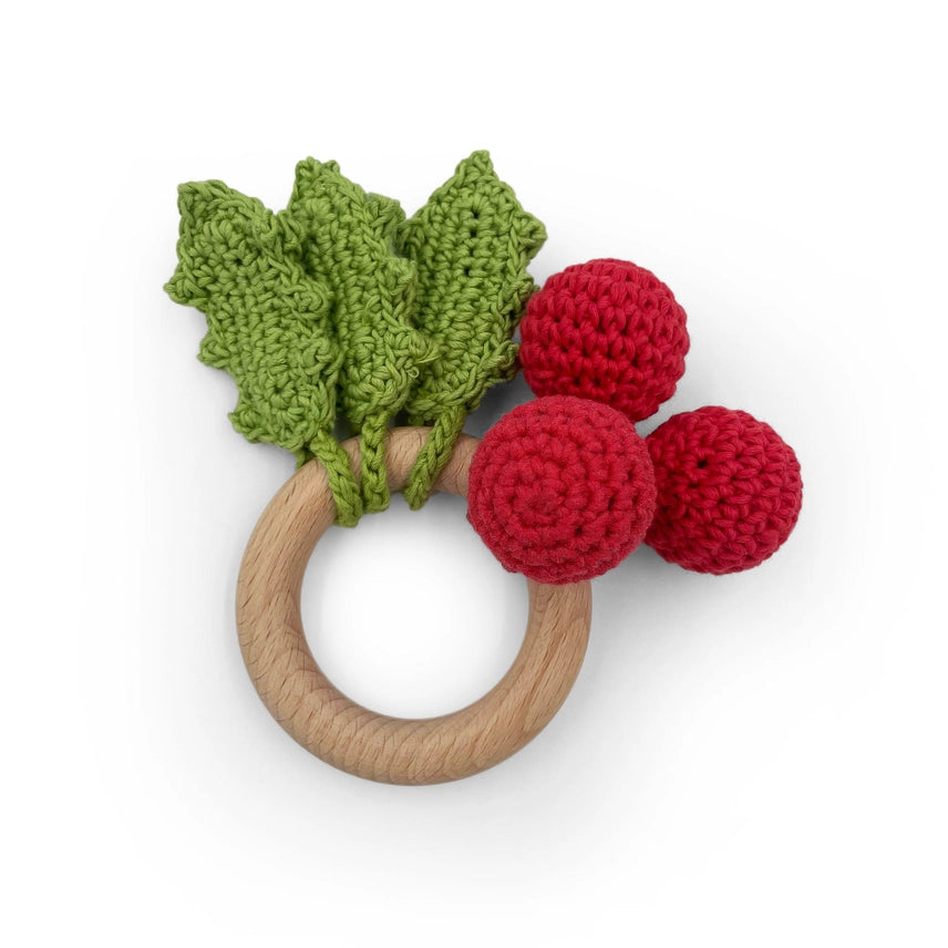 Wooden ring with three crocheted holly leaves and three red holly berries on a white background