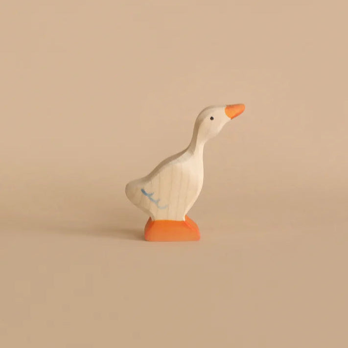 Wooden white goose toy figure on a light colored background