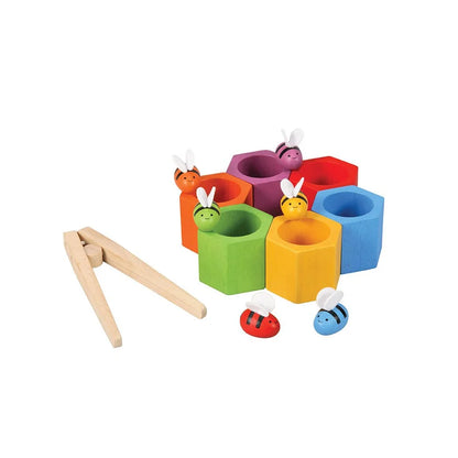 6 hexagonal wooden beehives arranged in a circle with wooden tongs and wooden bees on a white background