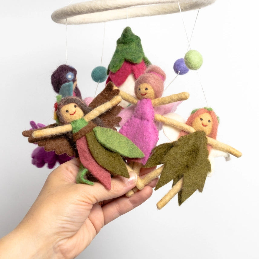 Hand holding three needle felted fairies attached to a mobile against a white background