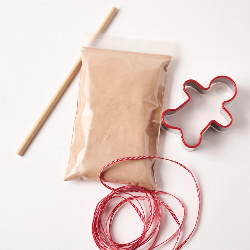 Gingerbread salt-dough, red string, and gingerbread man cookie cutter on a white background