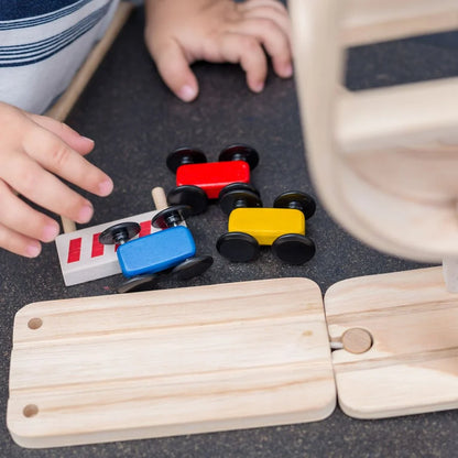 Wooden race track and blue, yellow, and red race cars on a dark gray table