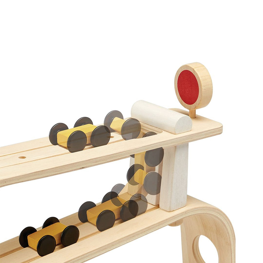 Wooden race ramp with a red stop sign and a yellow wooden car going down the ramp on a white background