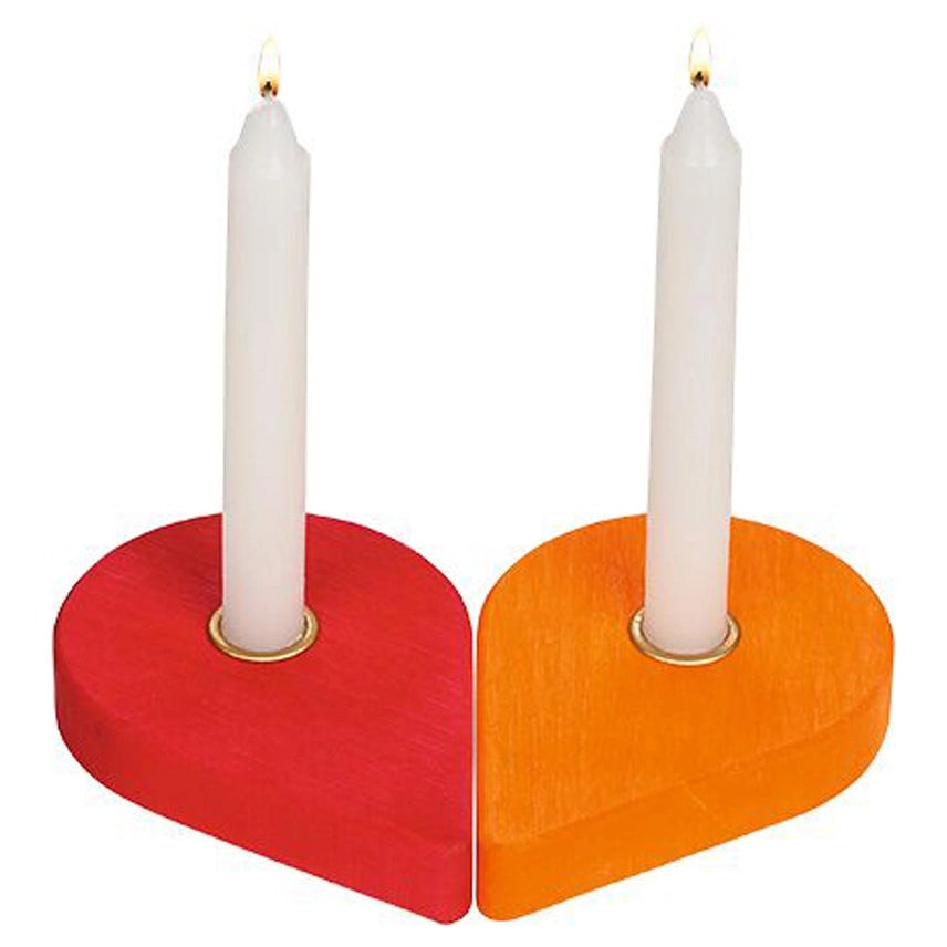 Two heart-shaped candle holders in red and orange, each holding a white taper candle with a small flame, shown on a plain white background.