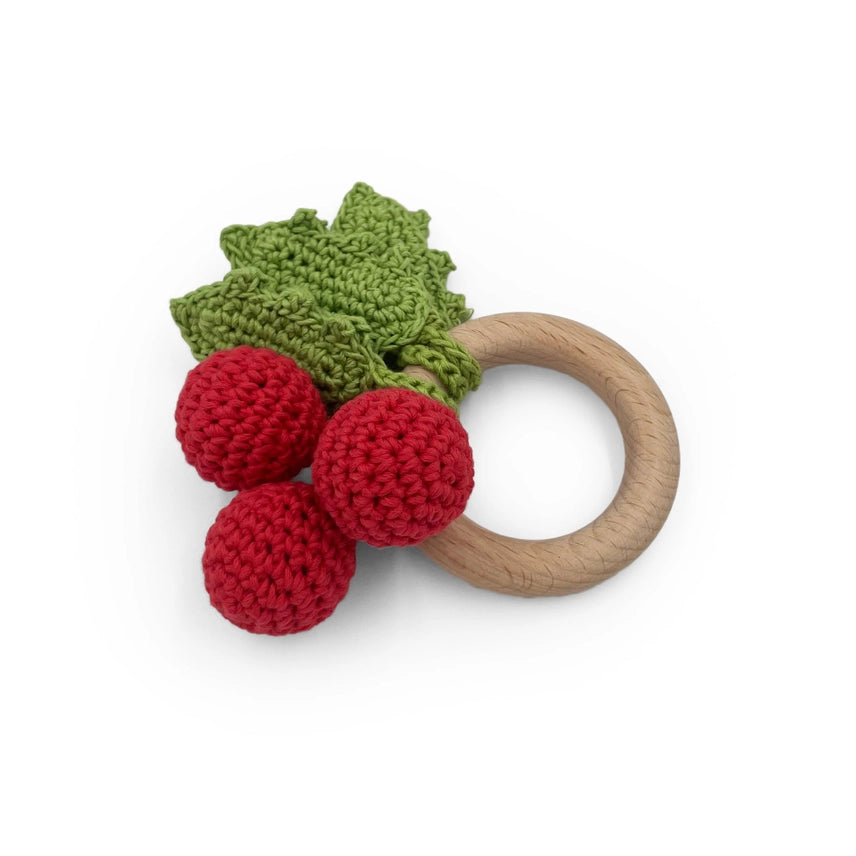 Holly berry teether with a wooden ring on a white background