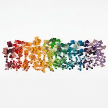 Pile of small wooden dots and L-shapes arranged in rainbow color order on a white background