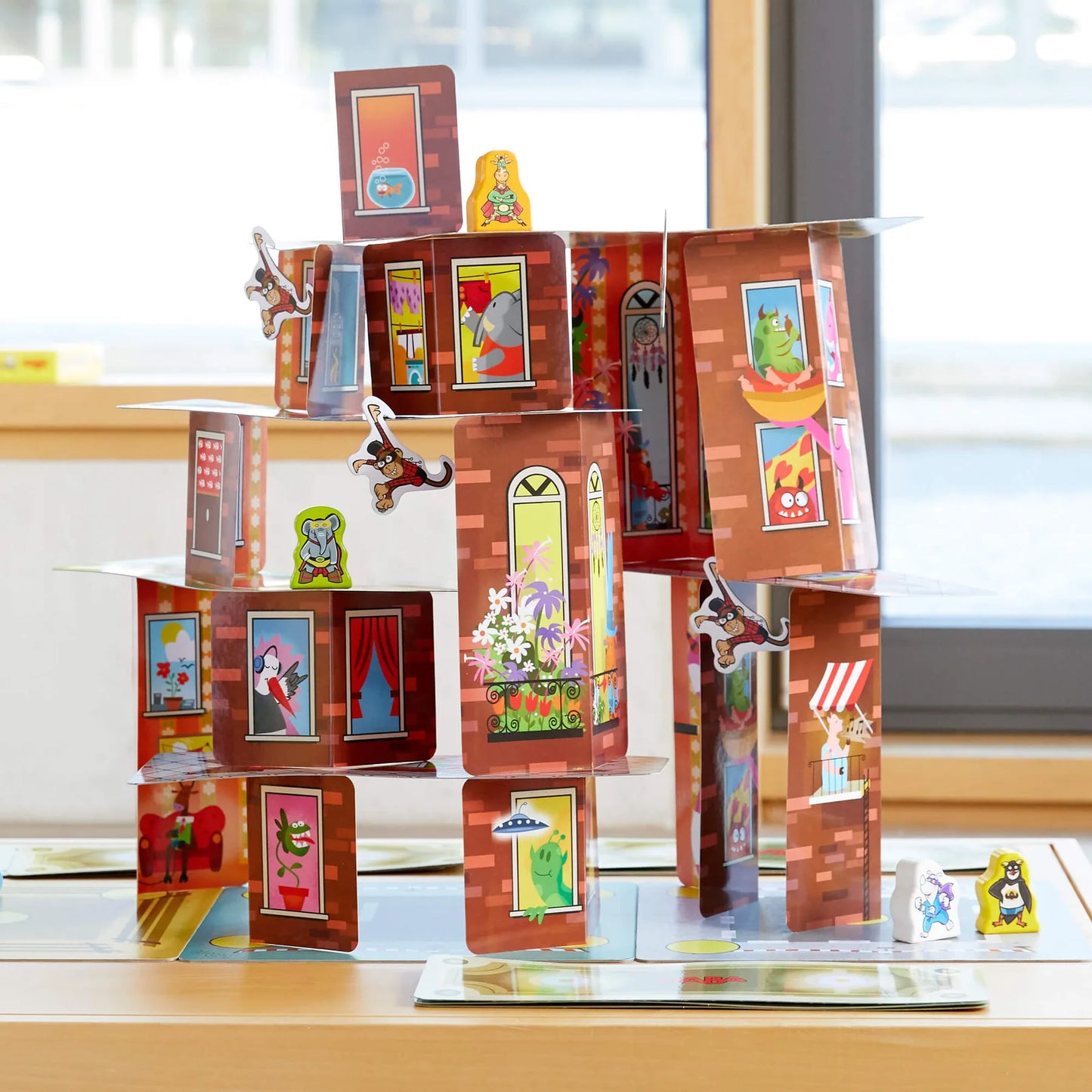 Game pieces from Rhino Hero Super Battle stacked high on a table in front of a window