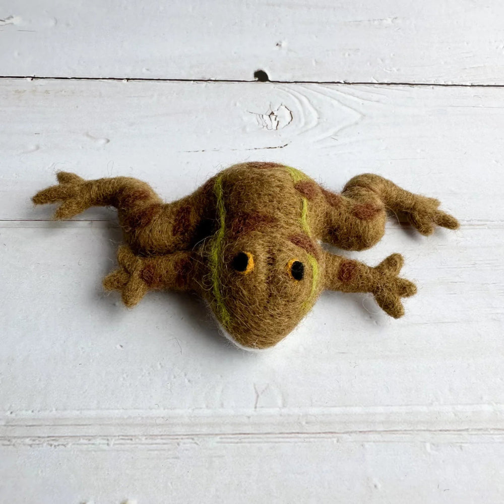 Felted wool frog toy on a white wooden surface