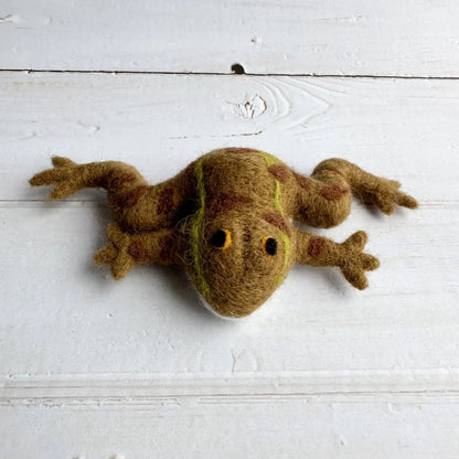 Felted wool frog toy on a white wooden surface