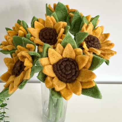 Felt sunflowers in a clear vase on a white background
