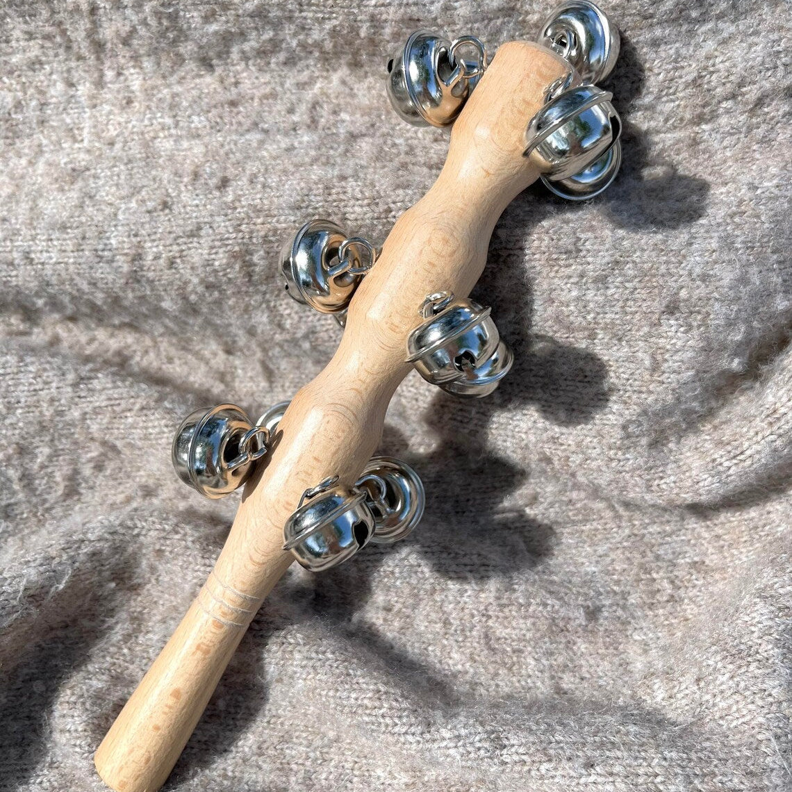Metal shaker wand with bells on a light fabric background