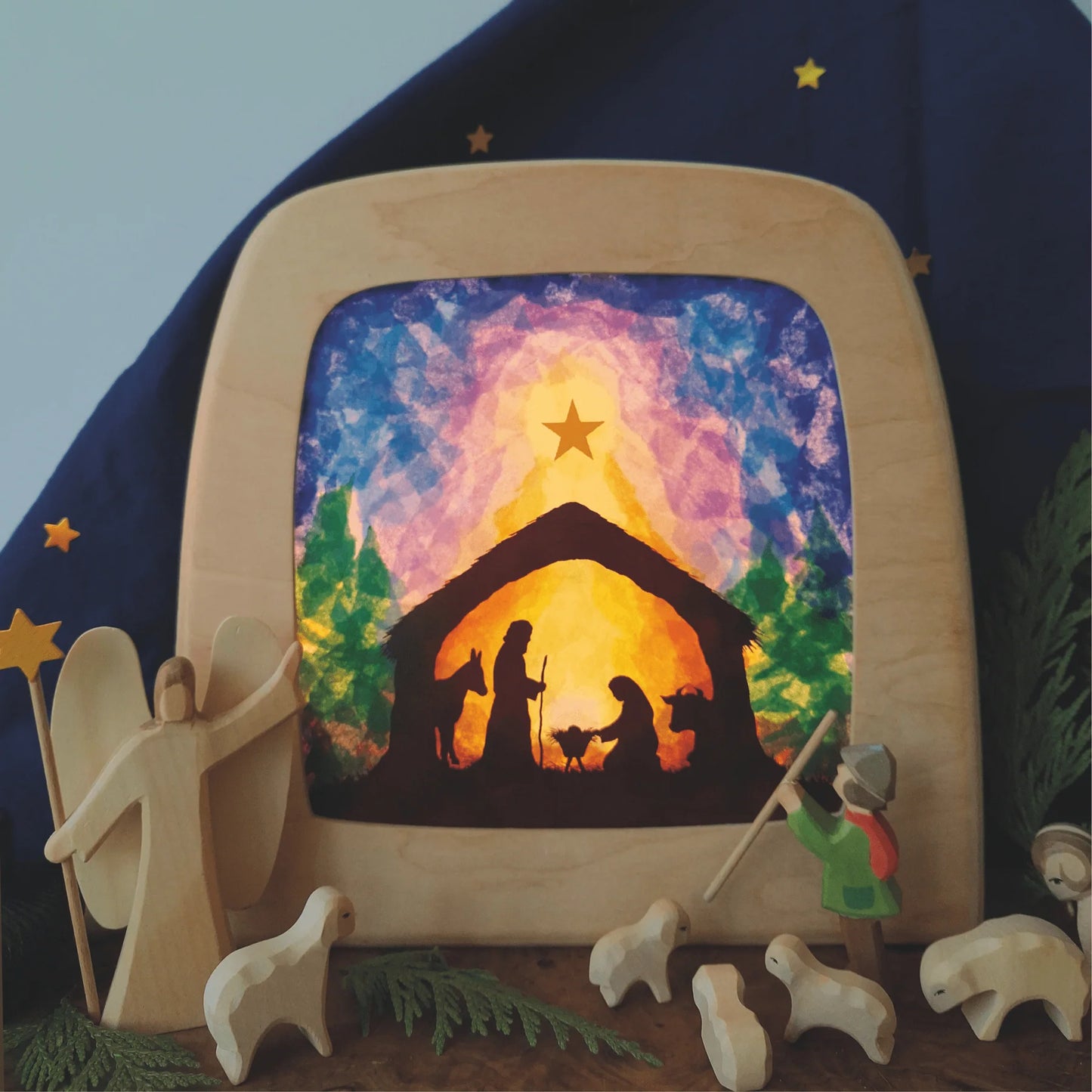 Nativity scene in wooden frame surrounded by wooden figures on a starry background