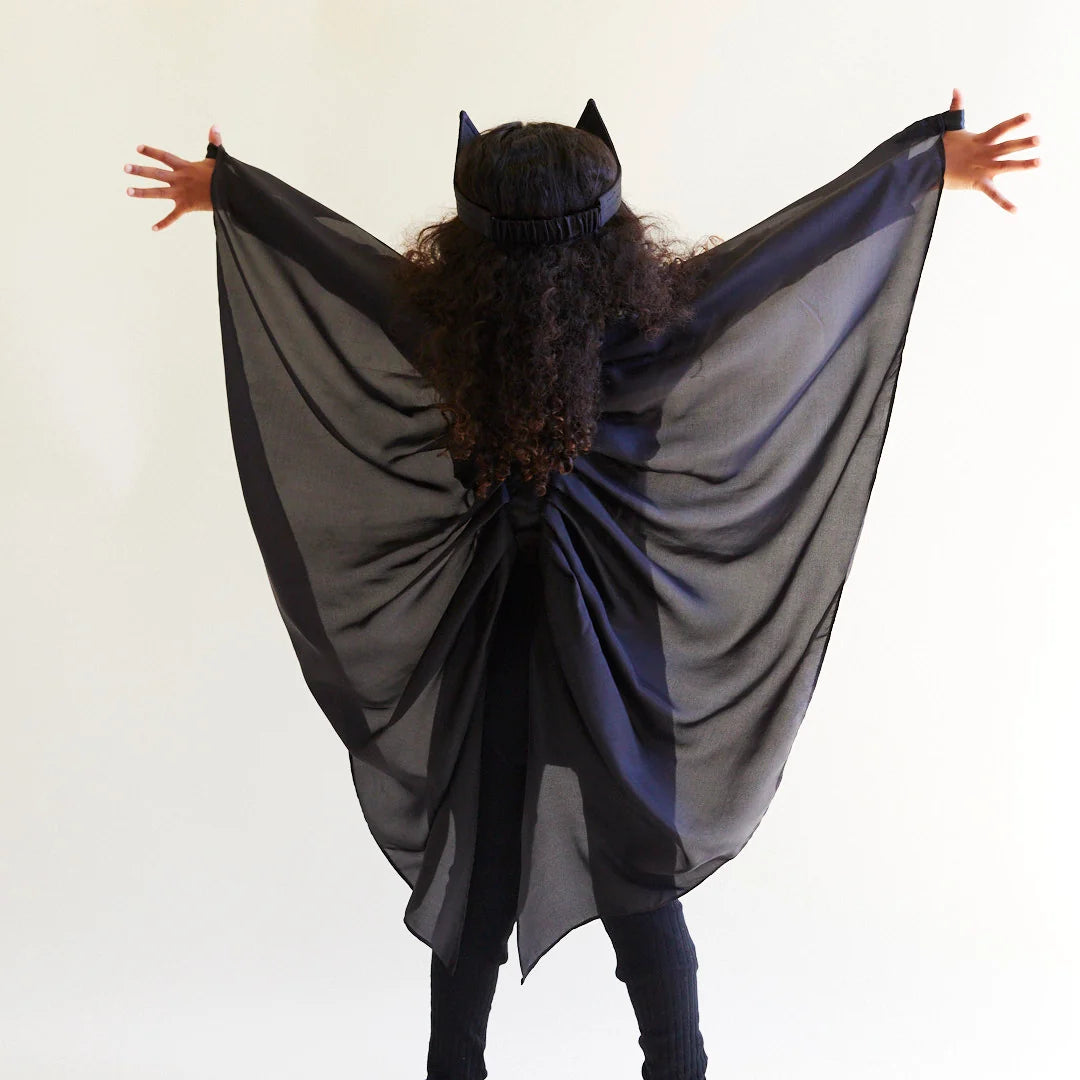 Child facing away from the camera, wearing black silk wings and a black bat ear headband