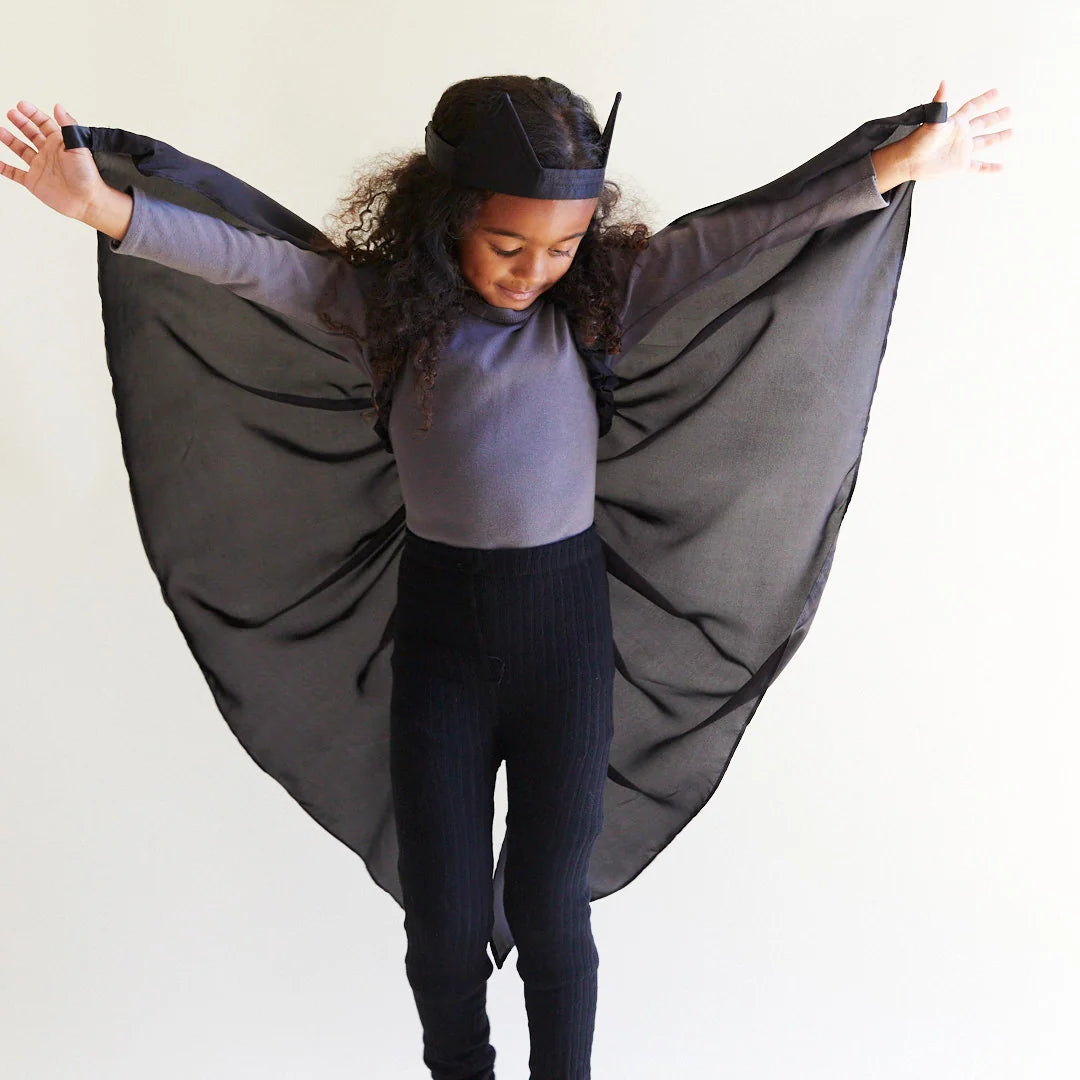Child wearing black silk wings and a black bat ear headband
