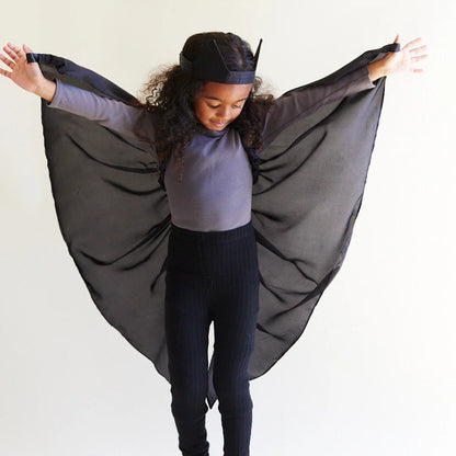 Child wearing black silk wings and a black bat ear headband