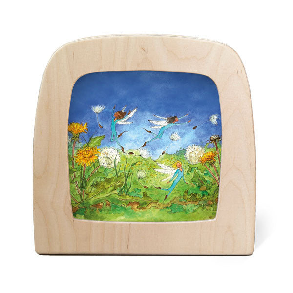 Wooden frame with silhouette of fairies flying around a field of dandelions