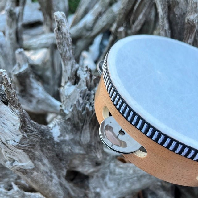 Close-up of a wooden drum with a white head, surrounded by driftwood.