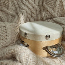 Small wooden tambourine with a white top on a knitted fabric background