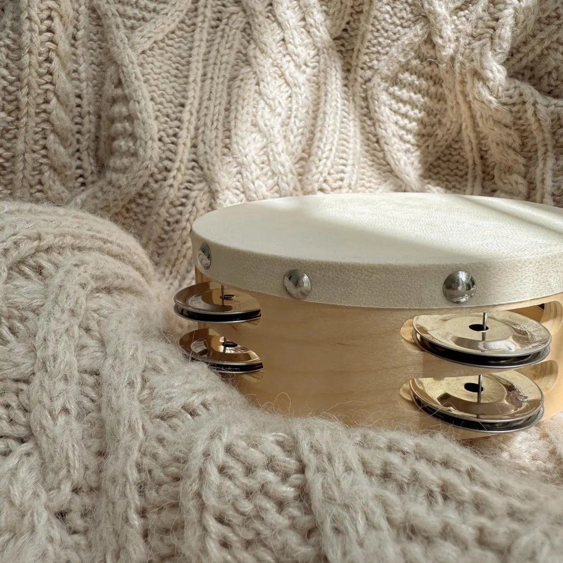 Wooden tambourine on a beige knitted fabric