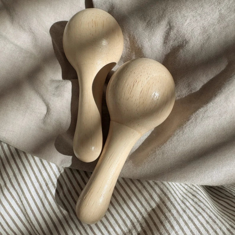Two wooden maracas laying on a neutral background
