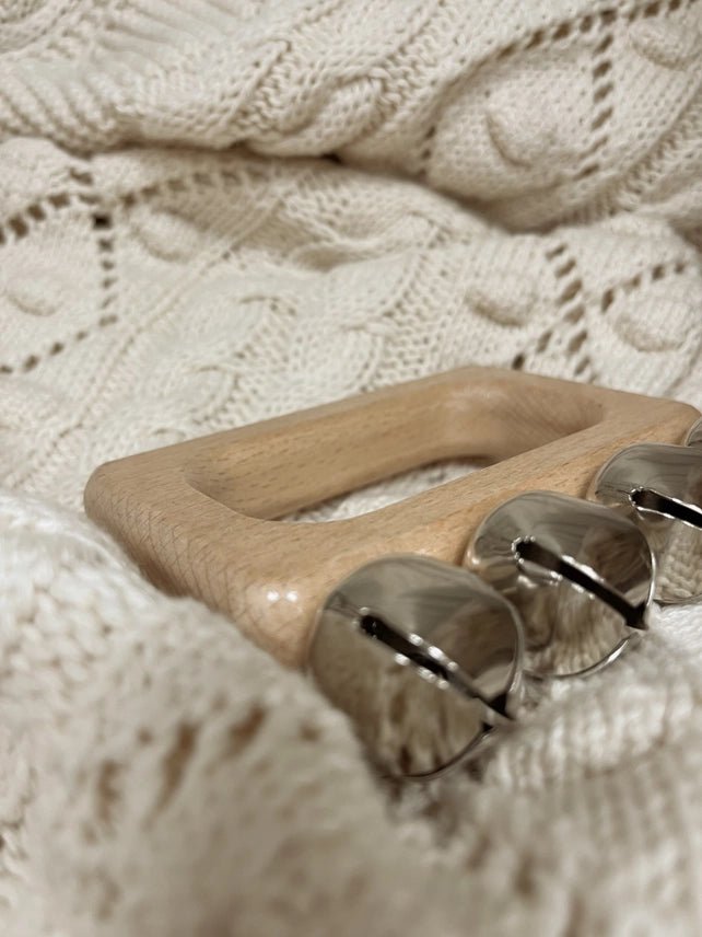 Wooden handle with metal bells on a textured beige fabric background