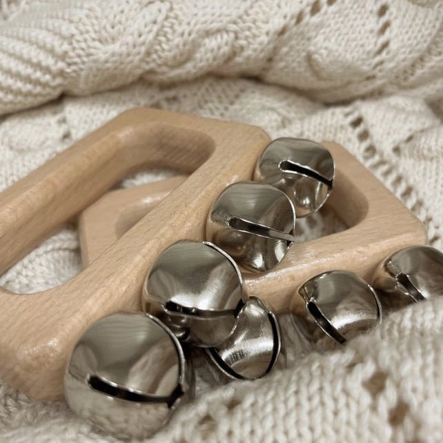 Wooden teething ring with metal bells on a textured beige fabric background