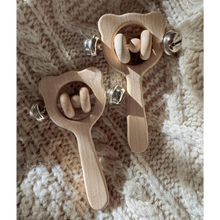 Two wooden baby rattle toys on a textured beige surface