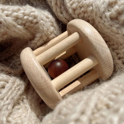 Wooden cylinder toy with ball in the middle on a crocheted background