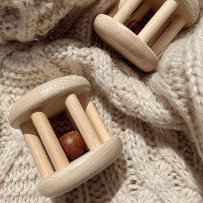 Two wooden baby rattles on a soft, textured fabric background