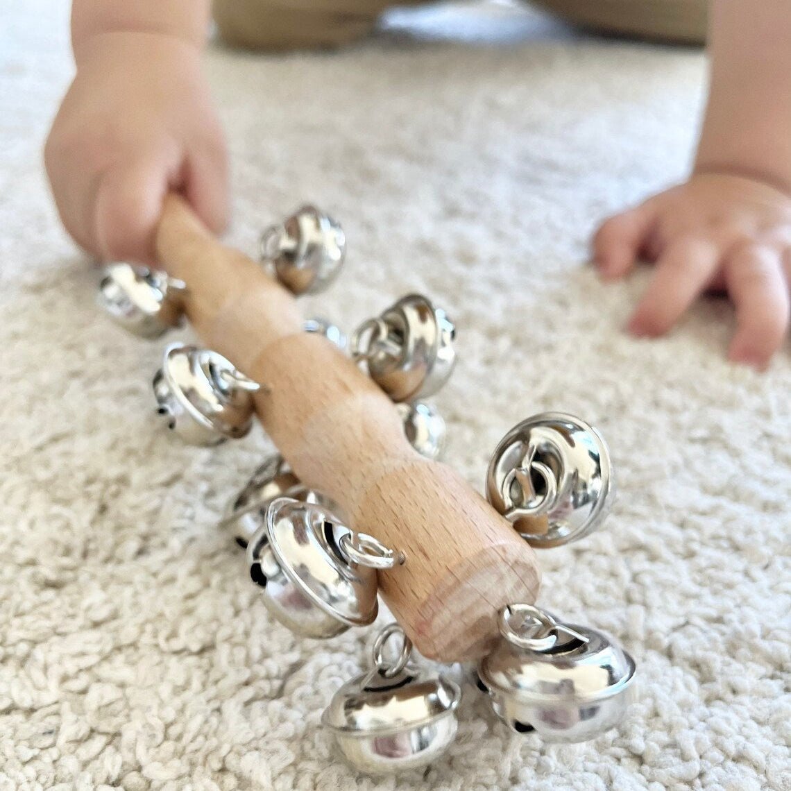 Child playing with a wooden rattle toy on a carpeted floor